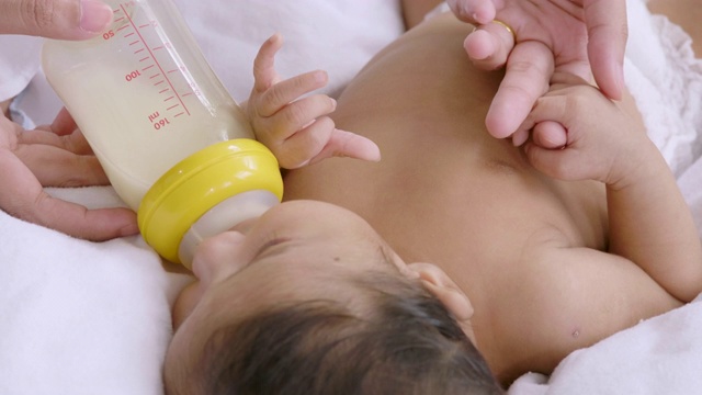 年轻的母亲用奶瓶喂新生儿视频素材