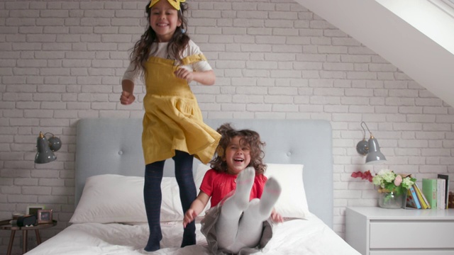 两个年轻的女孩在床上跳上跳下，笑着视频下载