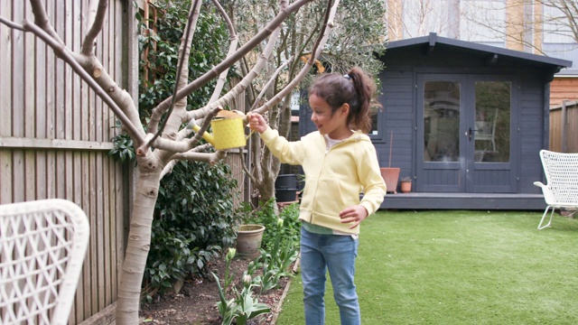 年轻女孩用喷壶浇花园视频素材