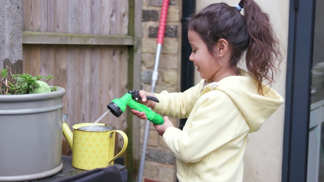 小女孩用水管往喷壶里灌水视频素材