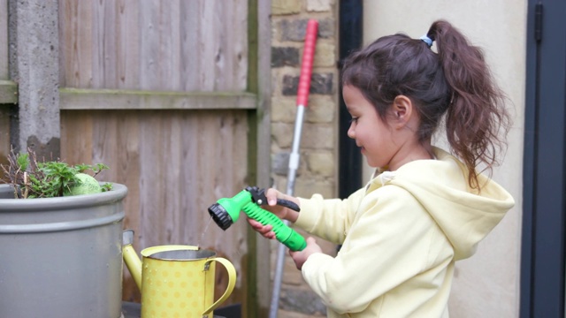 小女孩用水管往喷壶里灌水视频素材