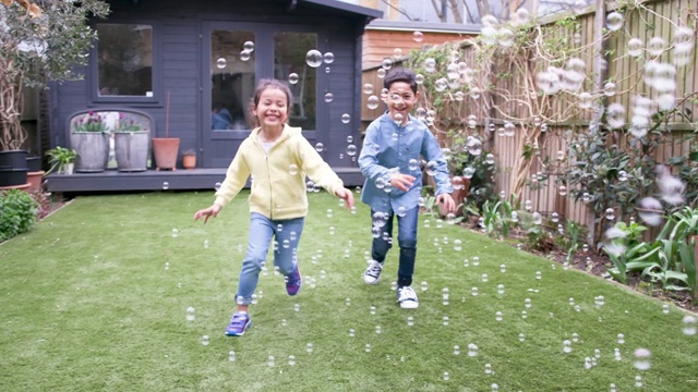 孩子们笑着，在花园里追逐着泡沫视频素材