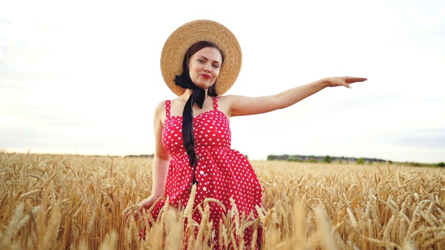 漂亮有趣的女孩穿着红色的衣服和草帽在金色的麦田里跳舞。成功，复古风格，快乐，幸福理念视频素材