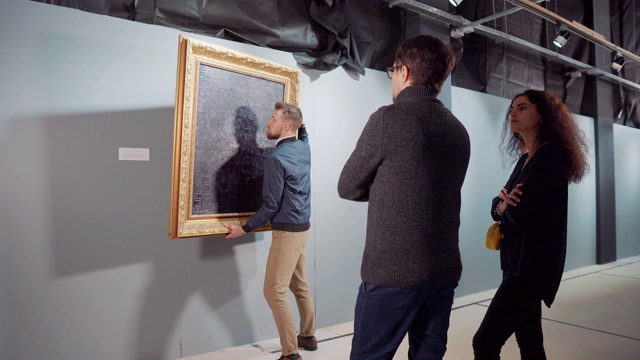 人们在画廊里看画，工人正在把画从大厅里抬走视频素材