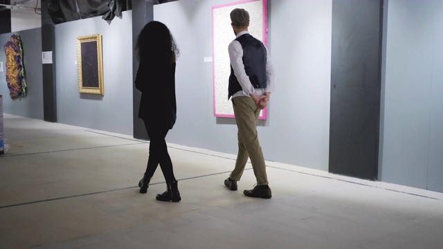 画廊的两位客人带着画走在大厅里视频素材