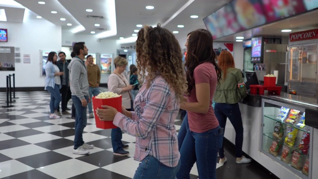 一群开心的女性朋友在电影院的小卖部买零食视频素材
