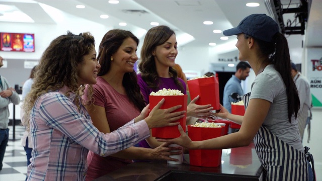 美丽的女性朋友微笑着在电影院小卖部买零食视频素材