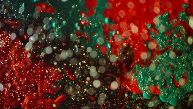 工作室拍摄的绿色红色颜料溅在黑色的背景工作室拍摄的抽象艺术视频素材