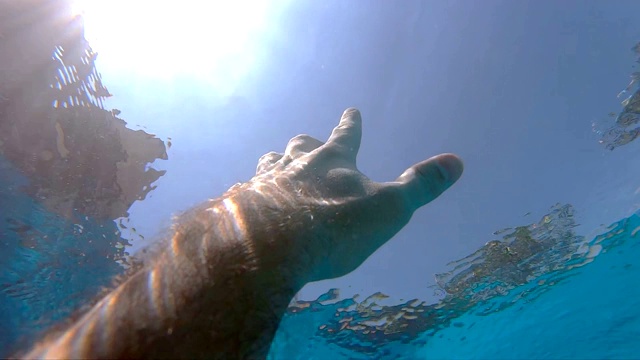 男性的手从水中伸展到阳光下。手臂请求帮助，试图触及太阳。人在海洋中溺水或漂浮到海面的观点。慢镜头观点视频素材