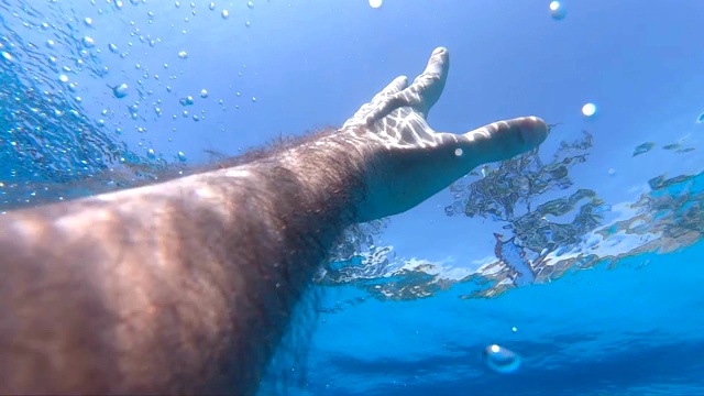 男性的手从水中伸展到阳光下。手臂请求帮助，试图触及太阳。人在海洋中溺水或漂浮到海面的观点。慢镜头观点视频素材