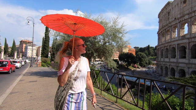 在欧洲的意大利罗马，一位女士打着遮阳伞走过圆形大剧场。——慢动作视频素材