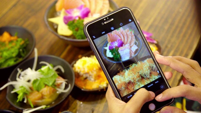 特写手的女人拍照鲑鱼生鱼片寿司日本食物在餐厅。视频下载