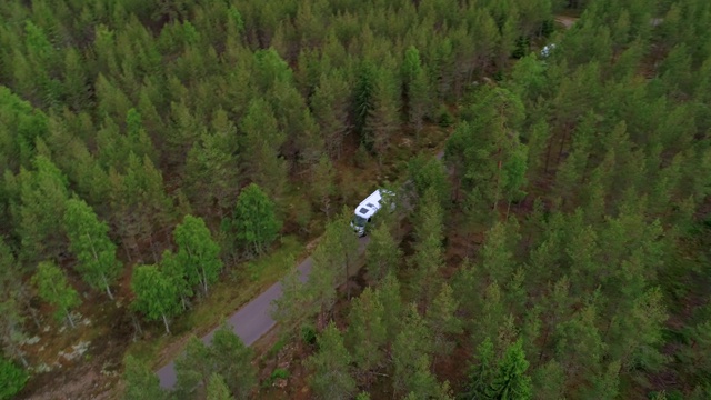 航拍:无人机拍摄露营车在瑞典斯马兰森林的树木上行驶视频下载