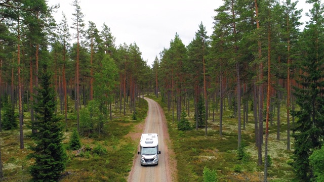 慢镜头:无人机拍摄的露营车行驶在道路中的树木在森林-斯马兰，瑞典视频下载
