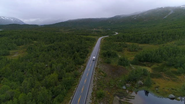 航拍:无人机拍摄的货车行驶在天空下的树木上——挪威奥普兰视频素材