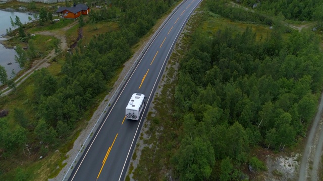 无人机拍摄的房车行驶在沿着树的道路上——挪威奥普兰视频素材