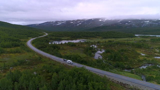 航拍:无人机拍摄在绿色景观中道路上的车辆-挪威奥普兰视频素材