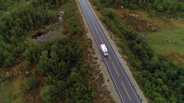 航拍:无人驾驶飞机拍摄在绿树环绕的道路上的车辆——挪威奥普兰视频素材