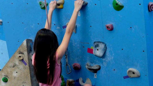 女孩穿着登山鞋和背带爬着攀岩墙视频素材