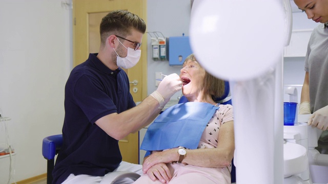 牙医在医院检查一位老年妇女的牙齿视频素材
