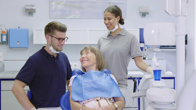 微笑的女人与牙医和护士在诊所视频素材