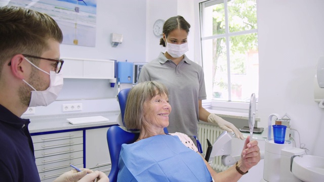 一个女人拿着镜子和牙医说话视频素材