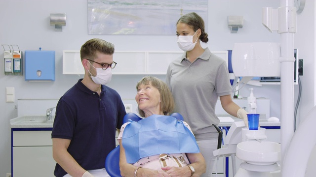 微笑的病人与牙医和护士在诊所视频素材