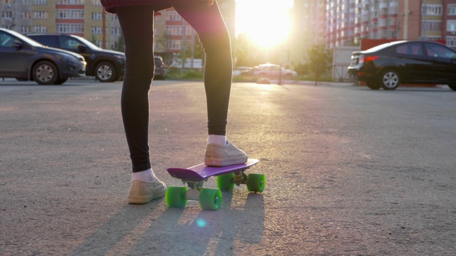 年轻的女孩滑板在城市街道上的阳光背景和城市建筑。在现代城市的阳光街道上骑滑板的少女。运动的生活方式。视频素材