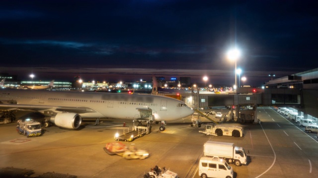 延时:黄昏时分，在机场，货运汽车将货物和行李装载到飞机上。放大照片视频素材