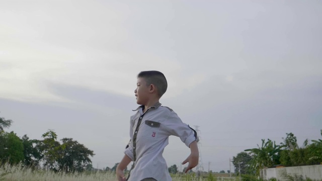 慢镜头亚洲小男孩跑着玩飞纸飞机视频素材