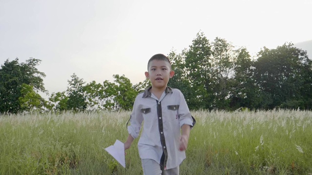 慢镜头亚洲小男孩跑着玩飞纸飞机视频素材