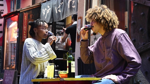 在日本居酒屋，一对年轻夫妇碰杯喝酒视频素材