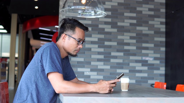 亚洲男人在咖啡馆用智能手机视频素材