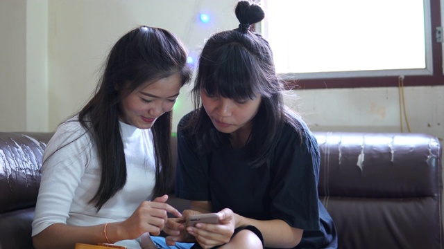 两个年轻快乐的女孩正在家里使用智能手机视频素材