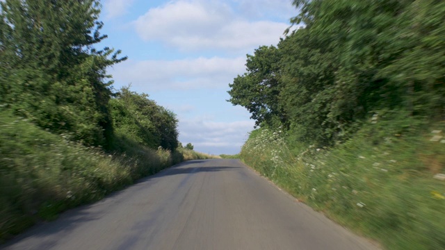 在一个阳光明媚的日子里，从汽车后部行驶在乡村道路上的观点。视频素材