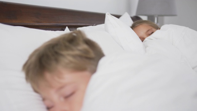 兄弟姐妹睡在舒适的4k家卧室的床上视频下载