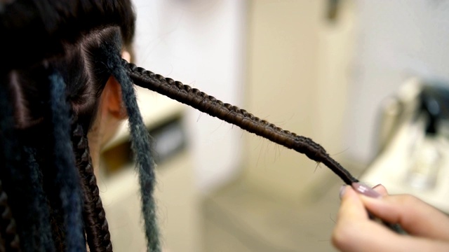 女孩发型师在沙龙里为客户编辫子视频下载