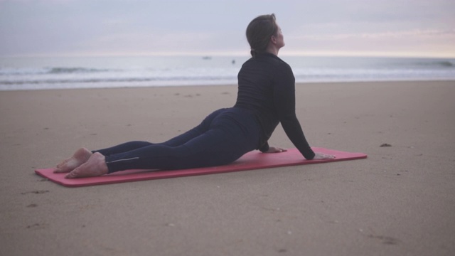 日落时分在大西洋的海滩上练习瑜伽的女人。视频素材