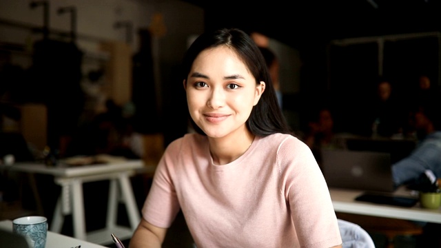 年轻的亚洲女性在繁忙的现代工作场所的肖像视频素材