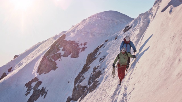 男性徒步旅行者在白雪覆盖的山坡上视频下载