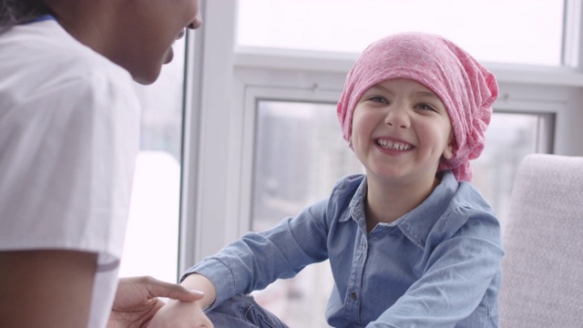 女医生坐在儿童病人与癌症斗争视频下载