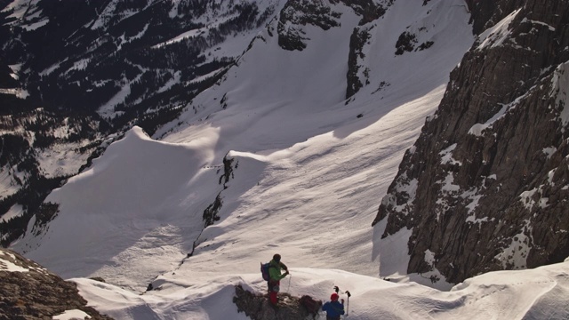 登山者在白雪皑皑的山上卷绕绳索视频素材