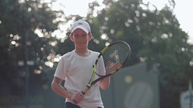网球运动员男孩的肖像拿着网球拍在室外球场，专业运动视频下载