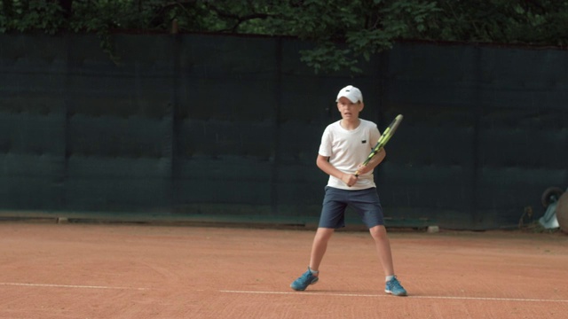 网球游戏，雄心勃勃的网球运动员青少年男孩集中精力，专注于游戏和球拍击球在红色的球场上视频下载