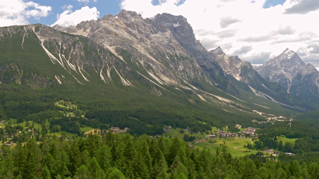 意大利Cortina d’ampezzo镇的山谷。白云石(意大利阿尔卑斯山)和松树林在山谷中对抗戏剧性的多云天空的全景。平移,4 k视频下载