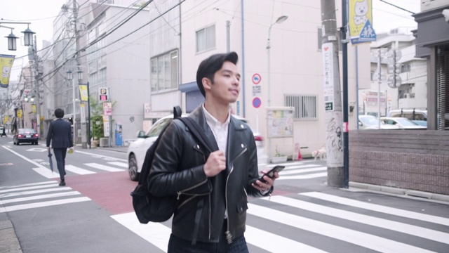 一个年轻的日本男人在东京边走边发短信视频素材