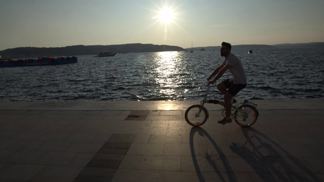 日出时分，一名男子在城市的街道上骑着自行车视频素材