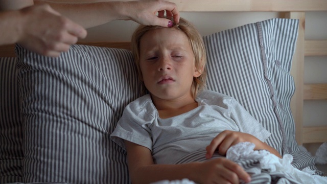 生病的小男孩躺在床上。母亲用精油软膏擦男孩的胸部。婴儿流感概念视频素材