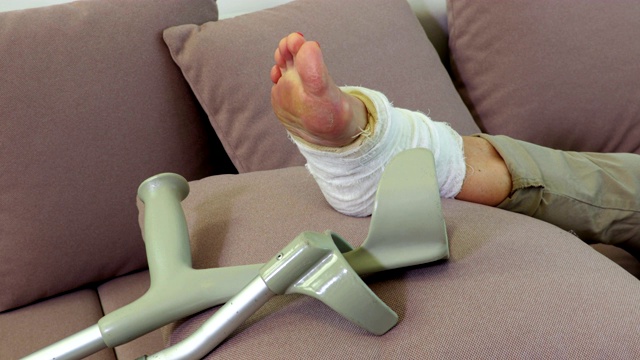 靠近沙发上女人受伤的腿和拐杖视频下载