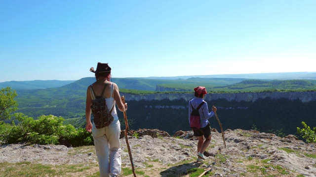 两个女孩旅行者女友走在一个高山高原上，欣赏惊人的景色。视频素材